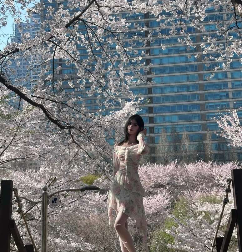 Maram in a floral dress and white sneakers among cherry blossoms