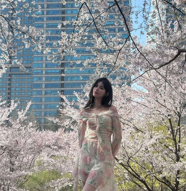 Maram in a floral dress framed by cherry blossom branches