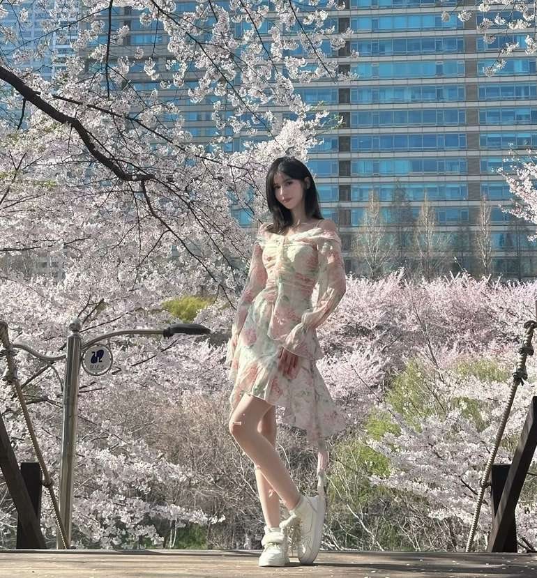 Maram in a floral dress standing in a blossom garden