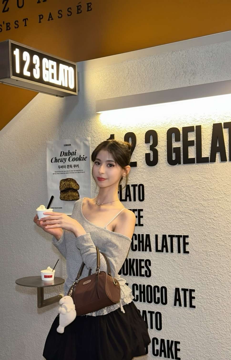 Maram holding a cup of gelato in a grey off-shoulder top